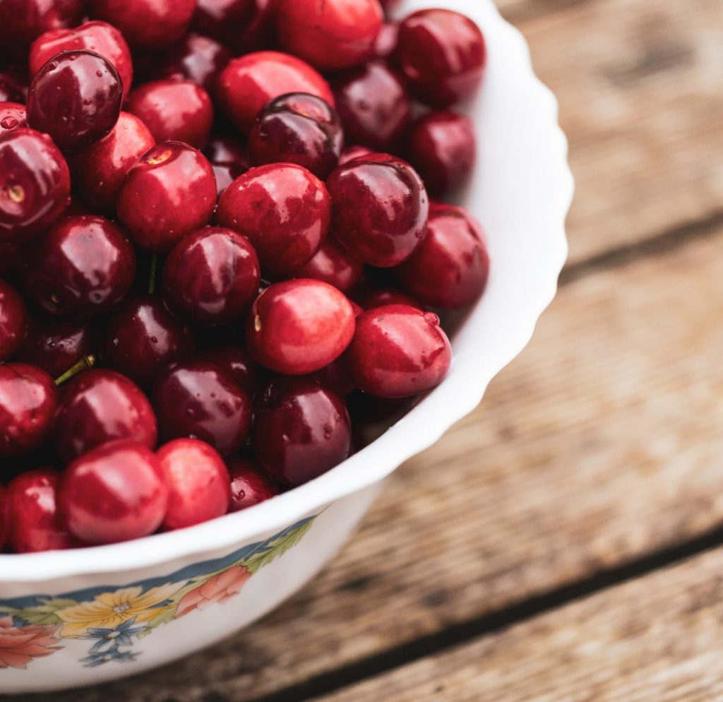 Ripe cherries in a bowl and on the table.