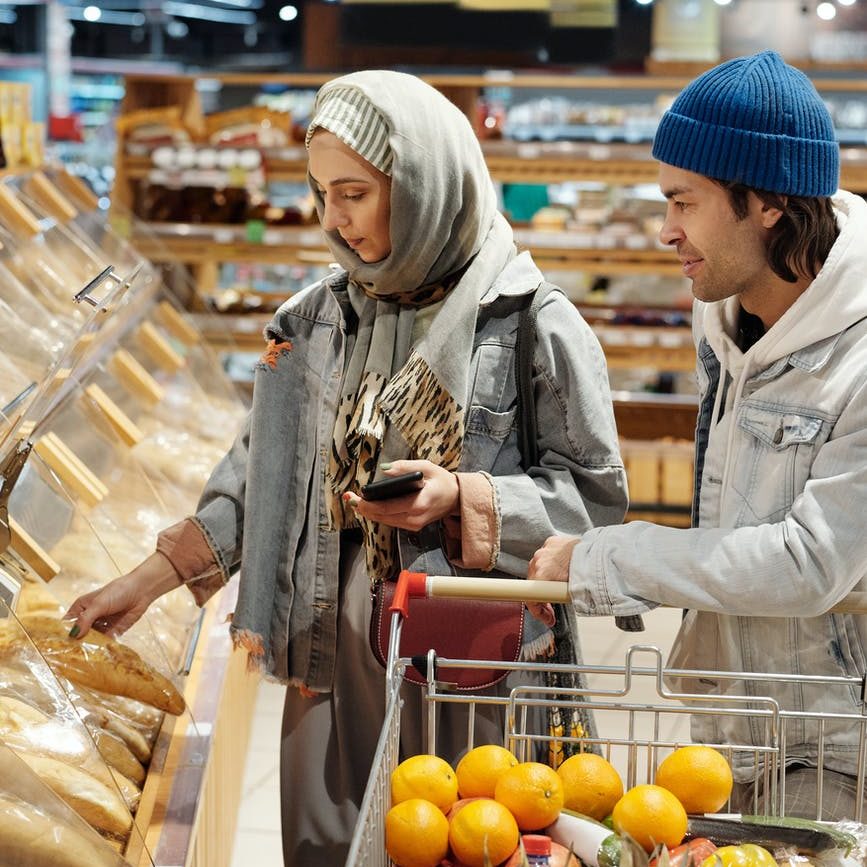 Couple with a shopping cart carefully selects bread with a good sell-by date (food date label).